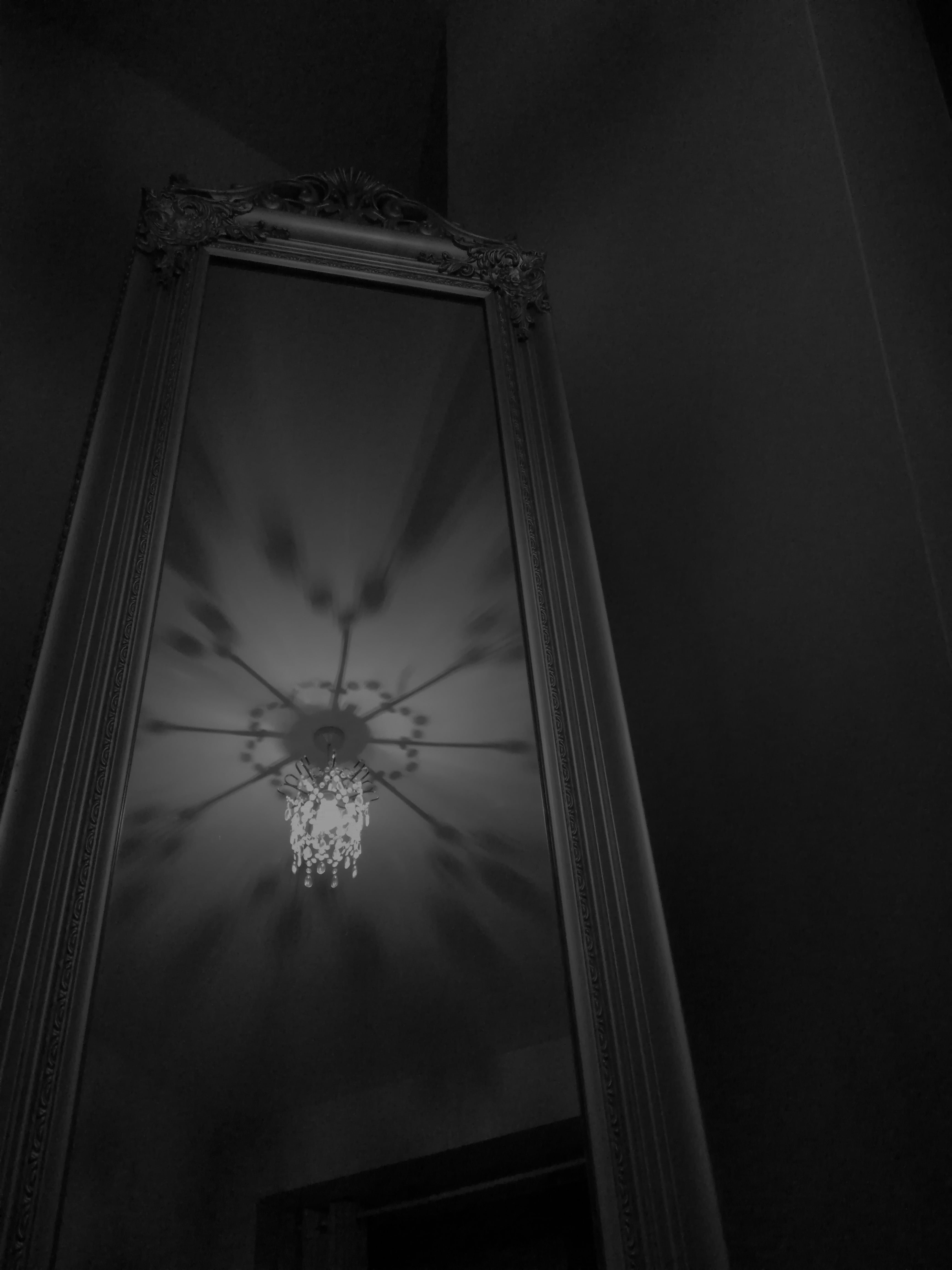 A black and white shot of the chandelier in my mothers room reflecting off of a standing mirror
